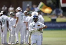 Dimuth Karunaratne raises his bat in celebration after scoring a century in his farewell Test against Australia.