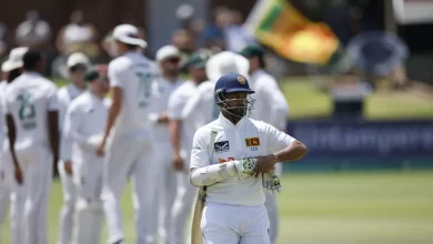 Dimuth Karunaratne raises his bat in celebration after scoring a century in his farewell Test against Australia.